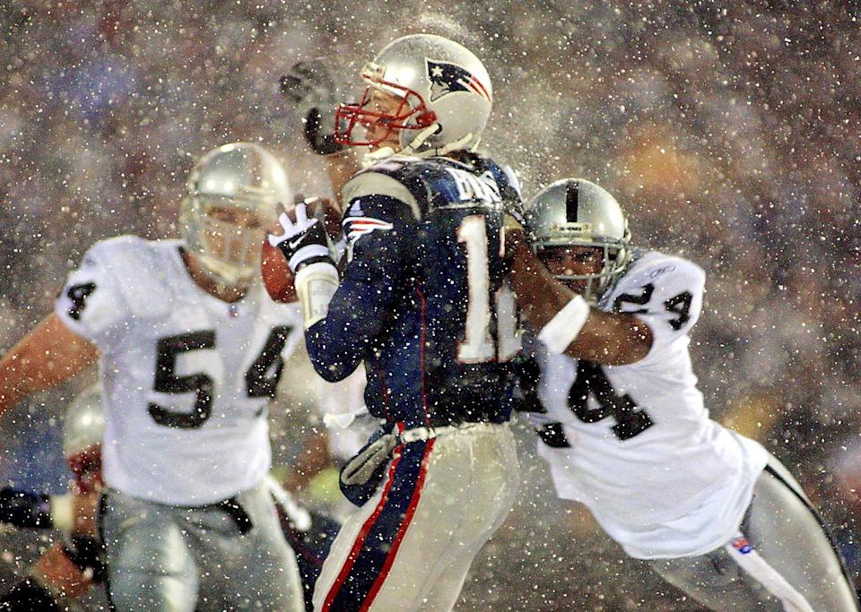 Patriots quarterback Tom Brady takes a hit from Charles Woodson (right) of the Raiders on a pass attempt in the last two minutes of the AFC divisional playoff game Jan. 19, 2002. The Patriots won 16-13 in overtime.