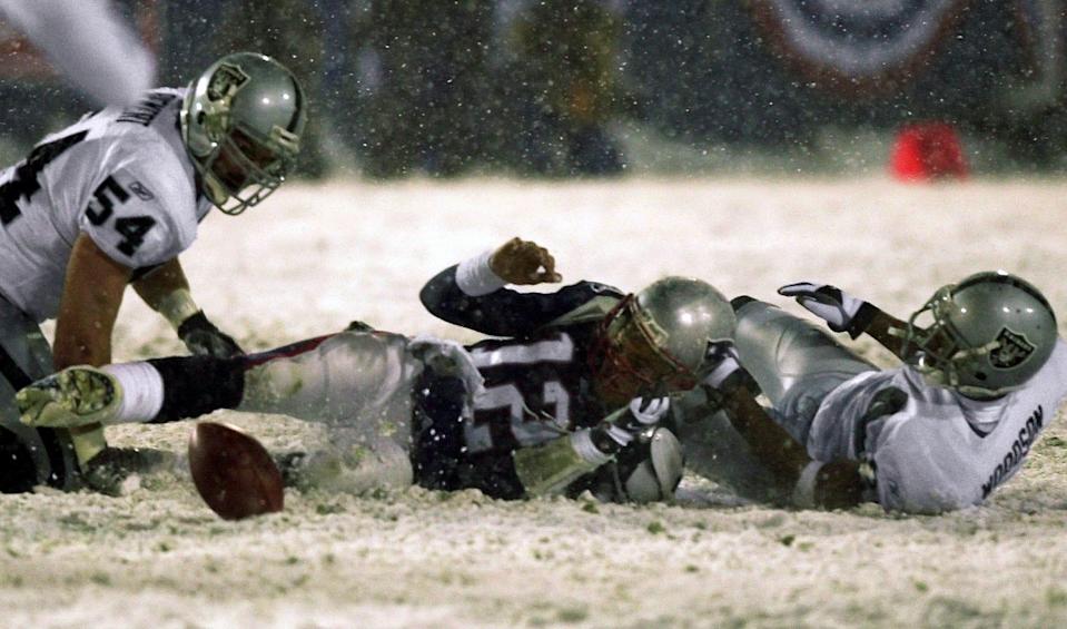 Patriots QB Tom Brady (12) loses the ball after being brought down by the Raiders' Charles Woodson, right, while Greg Biekert (54) looks to recover the football during the fourth quarter of the 2002 AFC divisional playoff game Jan. 19, 2002.