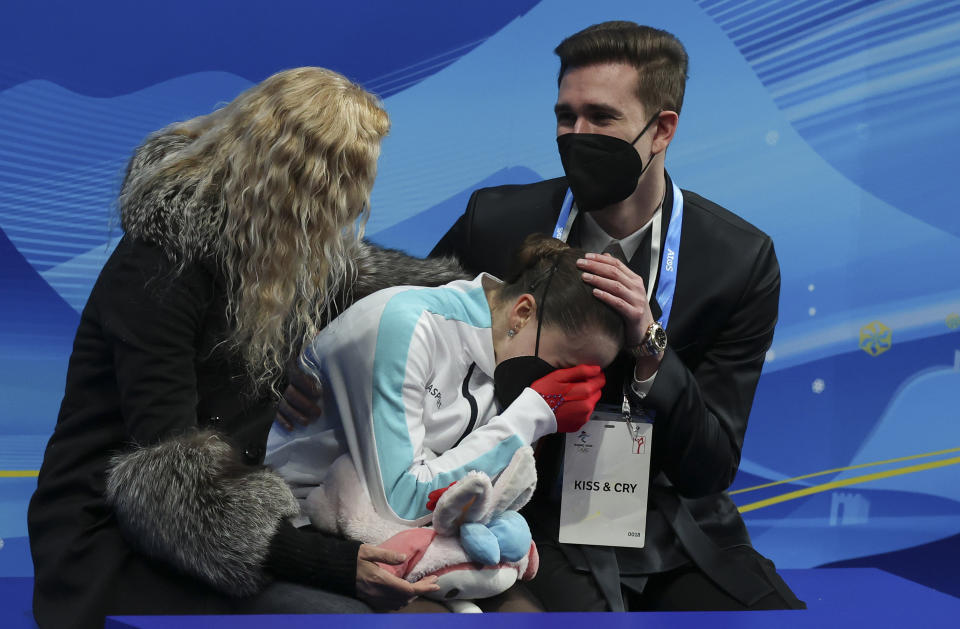 BEIJING, CHINA - FEBRUARY 17: Kamila Valieva of Russia reacts to her score with coach Eteri Tutberidze (L) and Daniil Gleikhengauz (R) at 'Kiss and Cry' during the Women Single Skating Free Skating on day thirteen of the Beijing 2022 Winter Olympic Games at Capital Indoor Stadium on February 17, 2022 in Beijing, China. (Photo by Jean Catuffe/Getty Images)