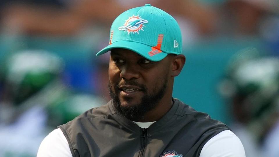 Brian Flores on field before game wearing Dolphins hat 2021