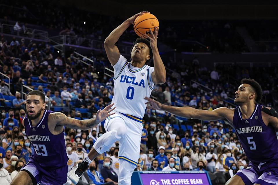 UCLA's Jaylen Clark drives past Washington's Terrell Brown Jr., left, and Jamal Bey for a dunk.