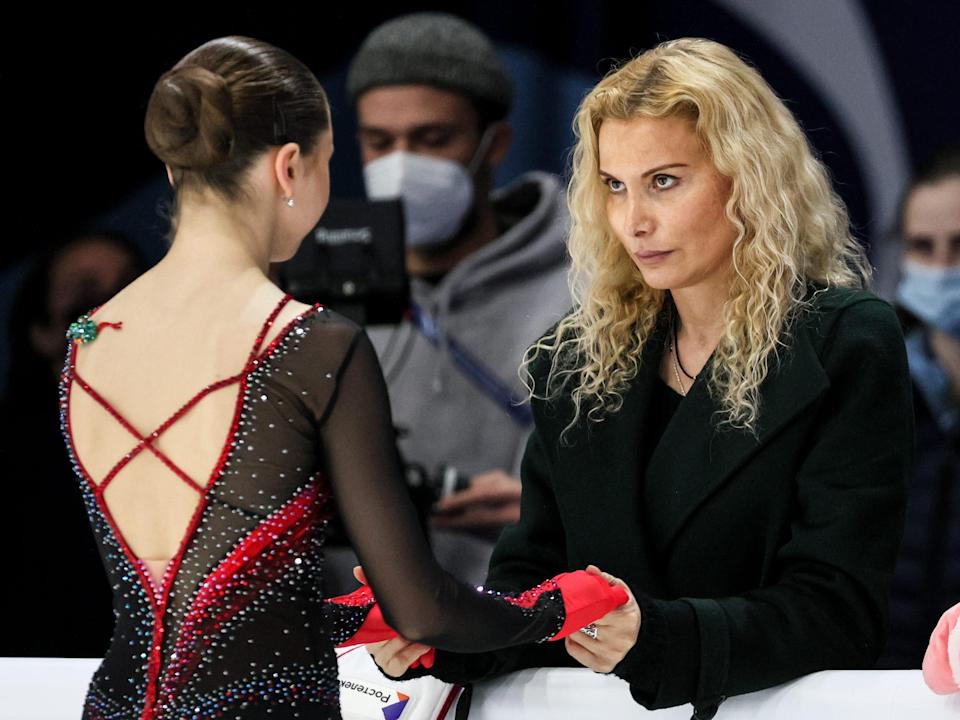 A woman stairs into the eyes of a younger skater, whose back is to the camera.