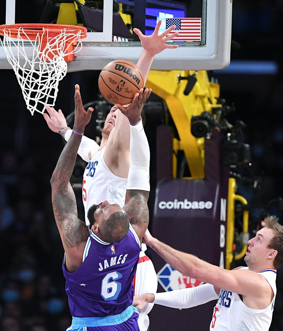 Lakers forward LeBron James attempts a layup while defended by Clippers guard Luke Kennard and center Isaiah Hartenstein.