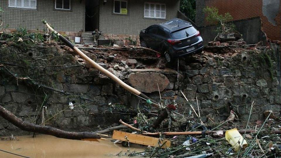 A car is seen hanging by a swept away street in Petrópolis, Brazil.