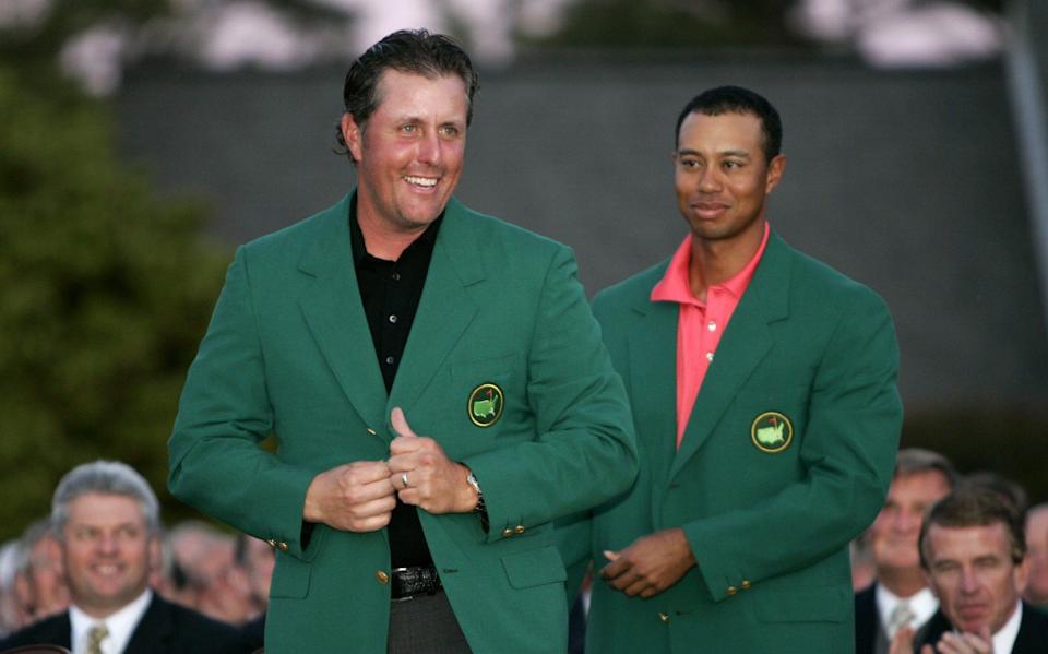 Mickelson of the US smiles after receiving green jacket from Woods after winning 2006 Masters golf tournament - Reuters