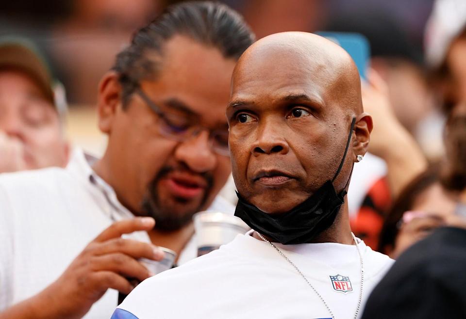 A serious-looking man with a black face mask under his chin.