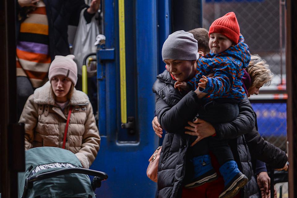 A woman carries a child as they exit a train arriving from Odessa at the Przemysl main train station in Poland after Russia invaded Ukraine. (Photo by Omar Marques/Getty Images)