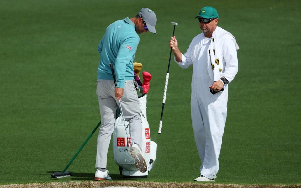 Adam Scott cleans his shoes after hitting a shot from the bunker on the second hole - Andrew Redington/Getty Images