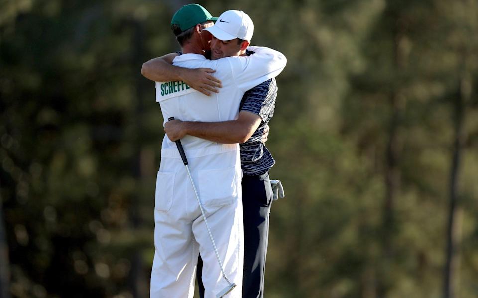 Scottie Scheffler and caddie Ted Scott embrace on the 18th green - GETTY IMAGES