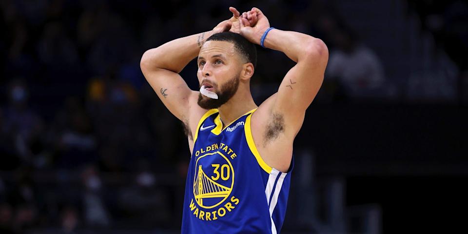 Stephen Curry looks up while holding his hands above his head during a game in 2022.