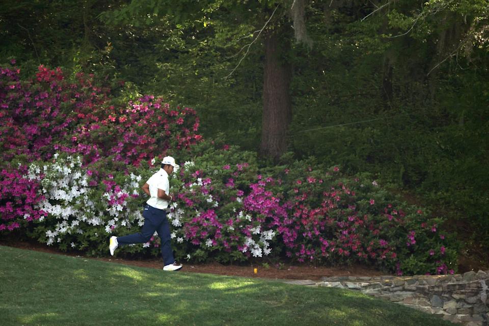 Hideki Matsuyama runs past the azaleas at the Masters.