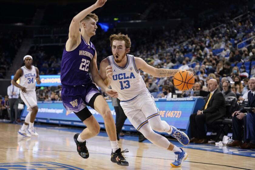 UCLA guard Jake Kyman (13) dribbles next to Washington guard Cole Bajema during the second half of an NCAA college basketball game Saturday, Feb. 19, 2022, in Los Angeles. (AP Photo/Marcio Jose Sanchez)