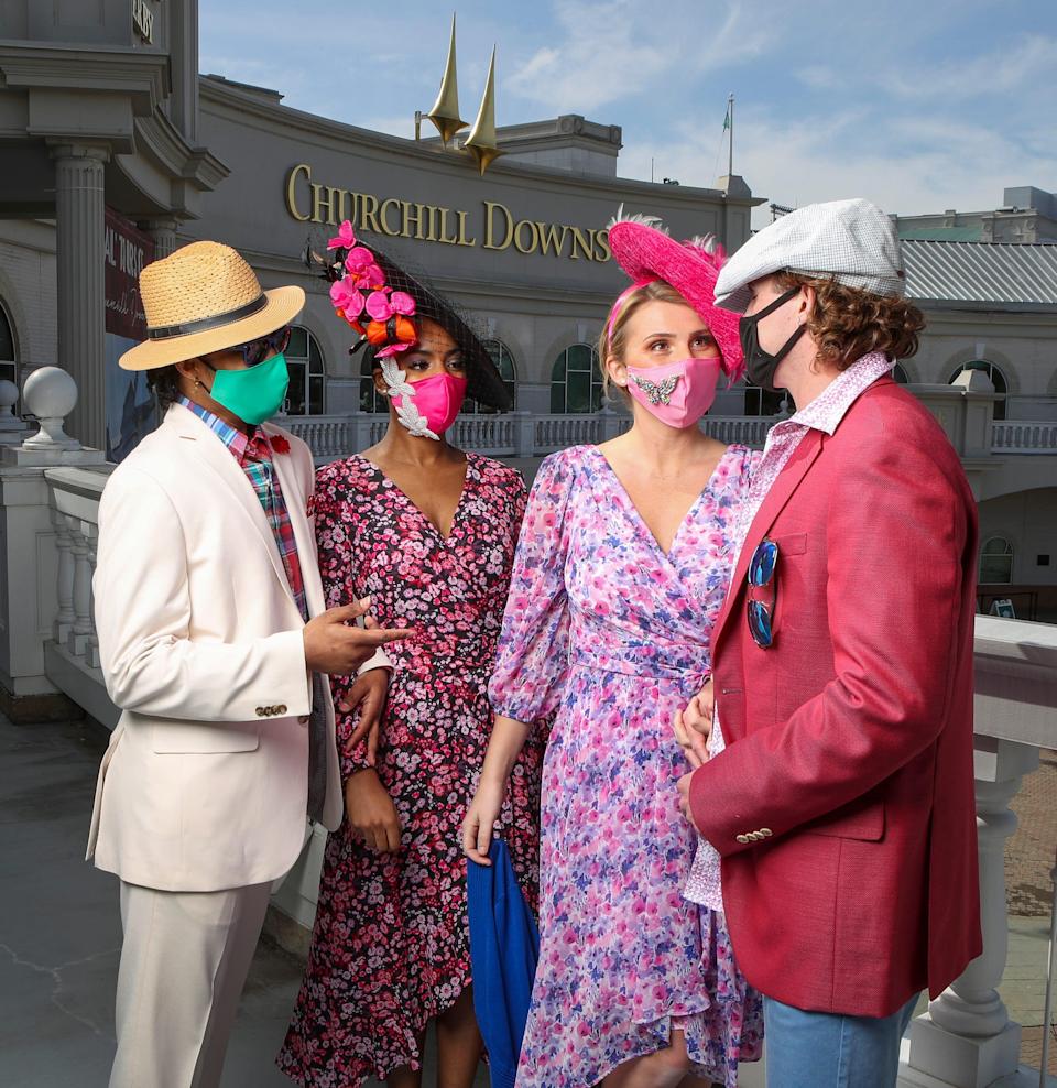 Our models are visiting the Kentucky Derby Museum. Description: Couple on the left, his ivory sport coat and trousers by Daniel Hecter; plaid shirt, Ralph Lauren; red boutineer, pocket square, straw fedora, navy sunglasses; all from Von Maur. Emerald green face mask by Kenzie Kapp. Her coral/hot pink floral on black dress, by Kenzie; hot pink see-through bag, by Kurt Geiger; black sinamay platter with hot pink and orange flowers, black netting, by Giavonnio; all from Von Maur. Pink satin face mask with pearl appliqués, by Kenzie Kapp.
Couple on the right; Her lavender/pink on white floral dress by DKNY; cobalt shrug; hot pink/gray/lavendar feathers on hot pink sinamay platter, by Frank Olive; all from Von Maur. Butterfy broach on pink face mask, by Kenzie Kapp.
His iridescent rose/blue linen sport coat by Peter Millar; Robert Graham shirt, pink Vineyard Vines T shirt, blue chino bermuda shorts by Tommy Bahamas; blue checked newsboy cap by Stetson, all from Von Maur.