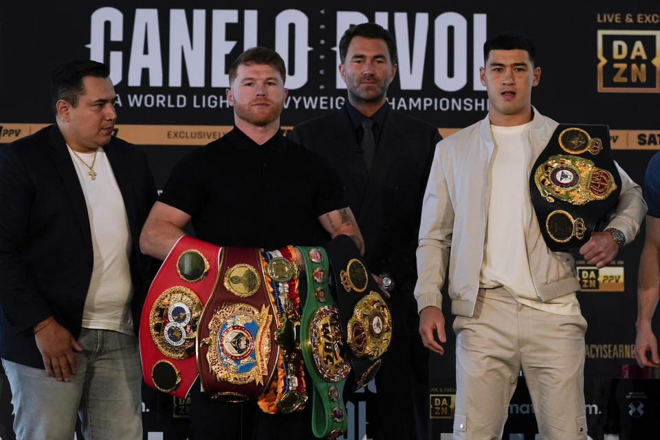 Canelo Alvarez, second from left, of Mexico, poses with Dmitry Bivol, right, of Russia, Wednesday, March 2, 2022, in San Diego as promoter Eddie Hearn, second from right, and Alvarez's trainer, Eddy Reynoso, left, look on. Alvarez is scheduled to fight Bivol in a boxing bout in Las Vegas on May 7. (AP Photo/Gregory Bull)