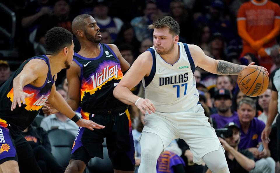 Dallas Mavericks guard Luka Doncic works the ball to the basket against Phoenix Suns guard Chris Paul, center, and guard Devin Booker during Game 1 of the Western Conference semifinal series on May 2, 2022, in Phoenix. (AP Photo/Matt York)