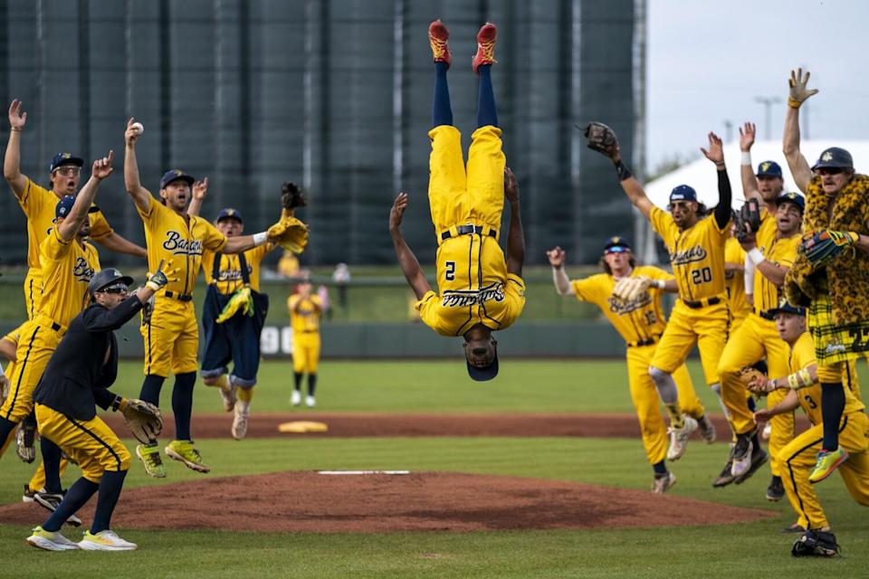 Savannah Bananas outfielder Malachi Mitchell flips on the field as his teammates cheer.