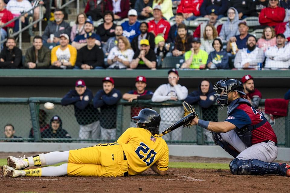 Savannah Bananas batter Breland Almadova lays on the ground during an at-bat as a pitch sails past him.