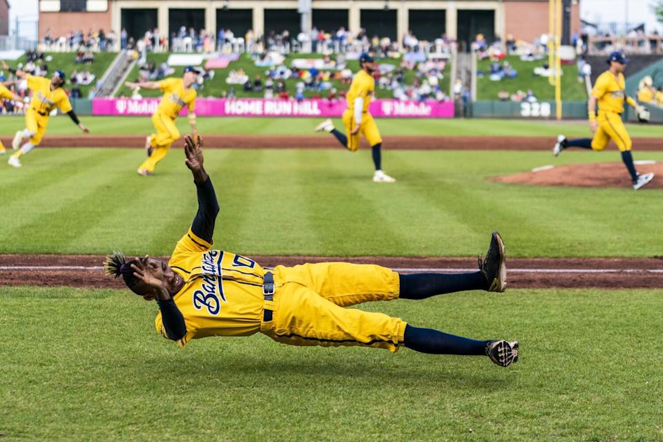 Savannah Bananas first base coach Maceo Harrison dances while the team sprints back toward home plate.