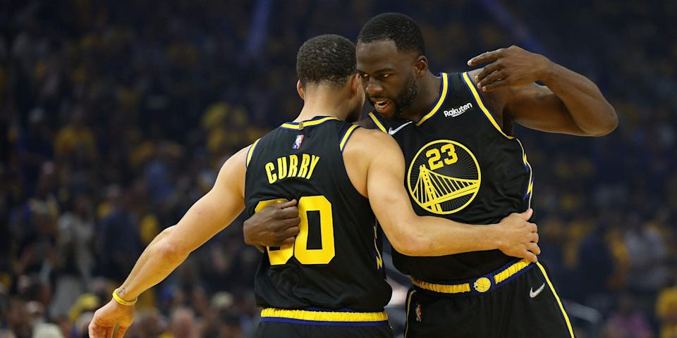 Stephen Curry and Draymond Green hug during a game.