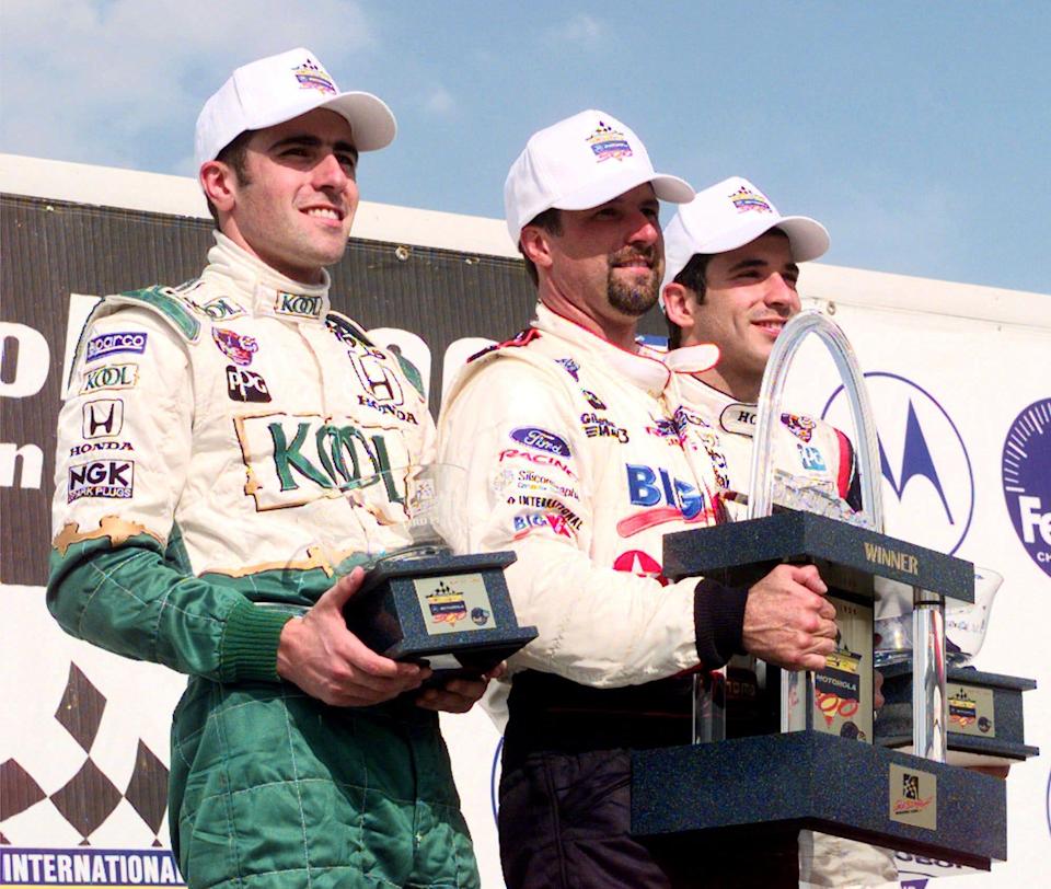 FILE – Michael Andretti (center) winner of the 1999 Motorola 300 held at Gateway International Speedway in Madison Ill. is flanked by Dario Franchitti left third place finisher and Helio Castroneves who finished second in the winner's circle May 29 1999.