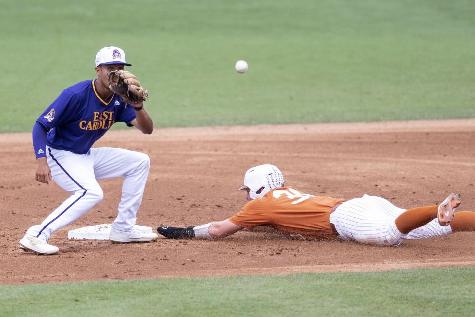 Texas' Eric Kennedy slides under the tag of East Carolina infielder Jacob Starling during a baseball game on June 11, 2022 in Greenville, N.C. The Longhorns and Pirates split the first two games on this NCAA super regional.