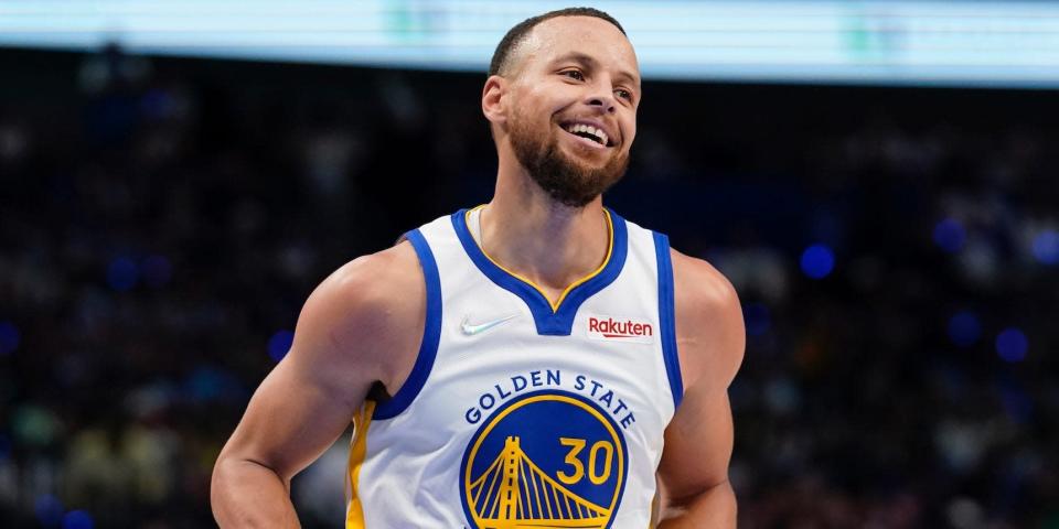 Stephen Curry smiles as he runs on the court.