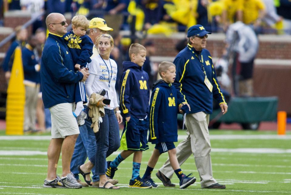 Former University of Michigan football coach Lloyd Carr, far right, leads his grandsons CJ and Tommy Carr, daughter-in-law Tammi Carr, and son Jason Carr, far left, holding his son Chad Carr, onto the Michigan Stadium field for the pregame coin toss, before an NCAA college football game against Oregon State in Ann Arbor, Mich., Saturday, Sept. 12, 2015. Chad Carr was diagnosed with an inoperable brain tumor.