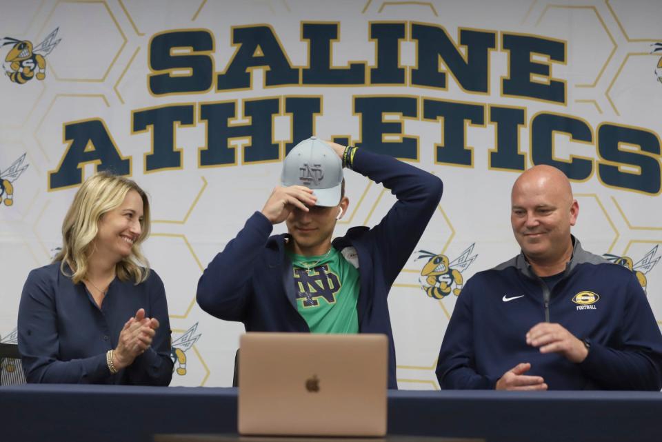 Saline QB C.J. Carr, grandson of former Michigan football coach Lloyd Carr, puts on a Notre Dame hat as he announces his commitment to Notre Dame at Liberty School in Saline on Thursday, June 9, 2022.