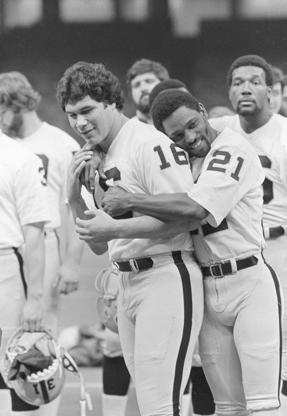 Oakland Raiders wide receiver Cliff Branch (21) hugs quarterback Jim Plunkett (16) as the Raiders lined up for a team picture before a workout in the Superdome in New Orleans., Jan. 21, 1981. (AP Photo/Paul Sakuma, File)