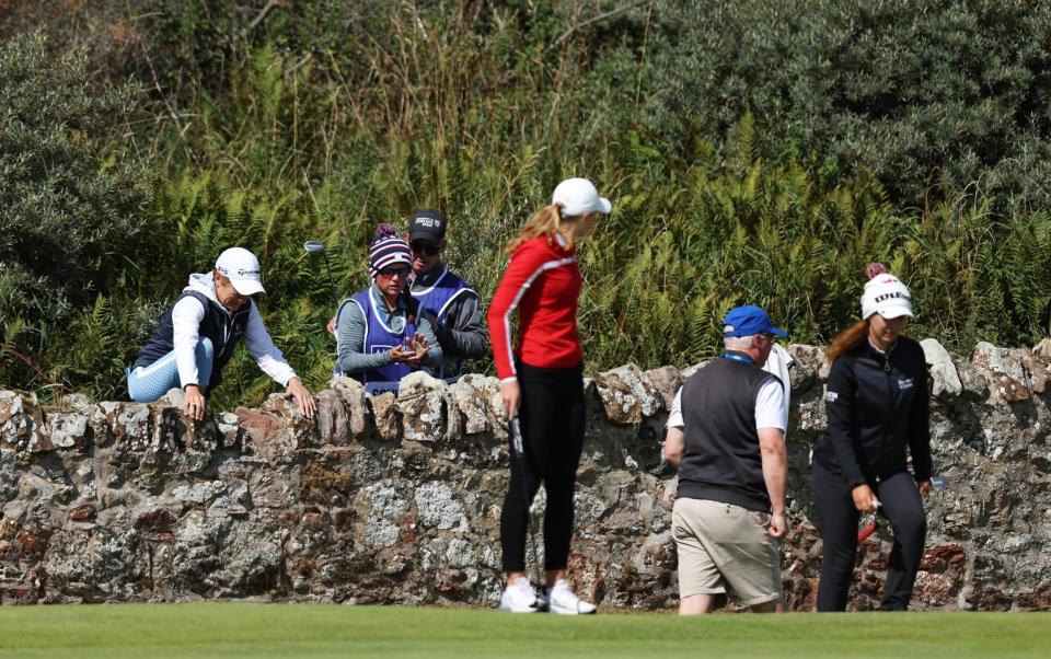 Catriona Matthew of Scotland and Caddies climb over a wall on the 2nd green whilst Louise Duncan of Scotland looks on during Day Two of the AIG Women's Open at Muirfield on August 05, 2022 in Gullane, Scotland. - GETTY IMAGES