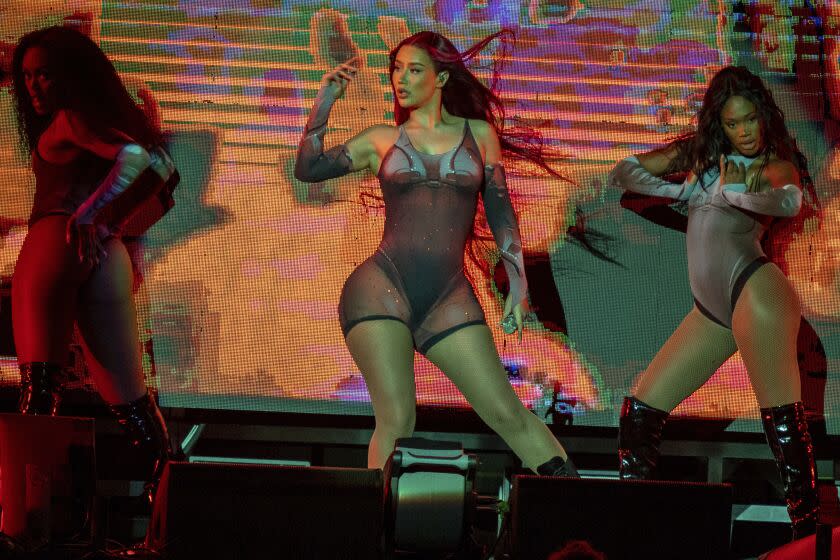 Three women dancing in bodysuits on a stage