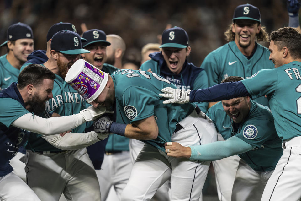 Seattle Mariners including Jesse Winker, left; Ty France, third from right; Logan Gilbert, second from right; and Adam Frazier, right celebrate a walkoff home run by Cal Raleigh against the Oakland Athletics on Sept. 30, 2022, in Seattle. The Mariners won 2-1 to clinch a spot in the playoffs. (AP Photo/Stephen Brashear)