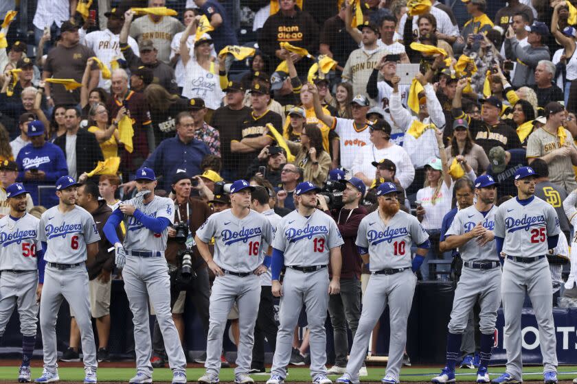 Dodgers players stand while being introduced as San Diego Padres fans wave towels