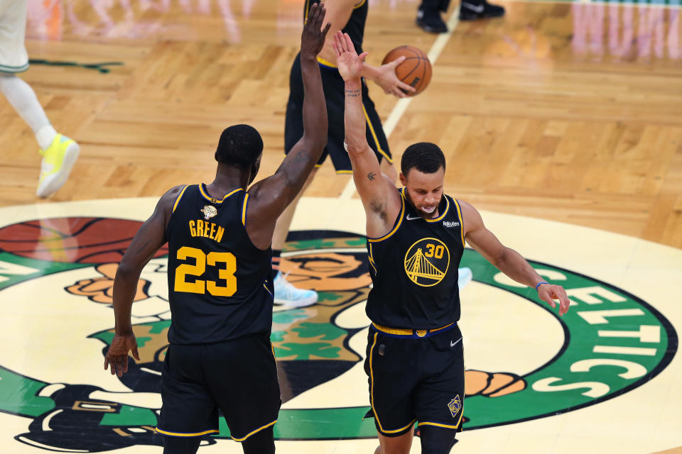 Boston - June 10: With the Celtics logo as a backdrop, the Warriors Stephen Curry (right) and Draymond Green (left) celebrate after the Golden State victory. The Boston Celtics host The Golden State Warriors in game 4 of the NBA Finals at TD Garden in Boston on June 10, 2022. (Photo by Jim Davis/The Boston Globe via Getty Images)