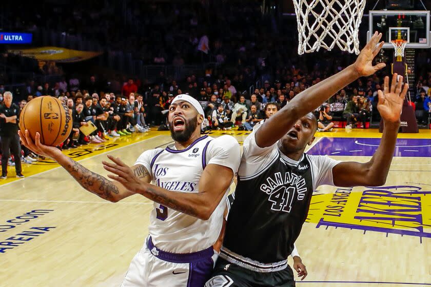 Los Angeles Lakers forward Anthony Davis, left, shoots under pressure from San Antonio Spurs forward Gorgui Dieng.