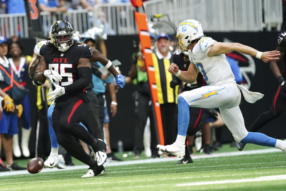 Atlanta Falcons defensive tackle Ta'Quon Graham (95) fumbles the ball ahead of Los Angeles Chargers quarterback Justin Herbert (10) during the second half of an NFL football game, Sunday, Nov. 6, 2022, in Atlanta. (AP Photo/John Bazemore)