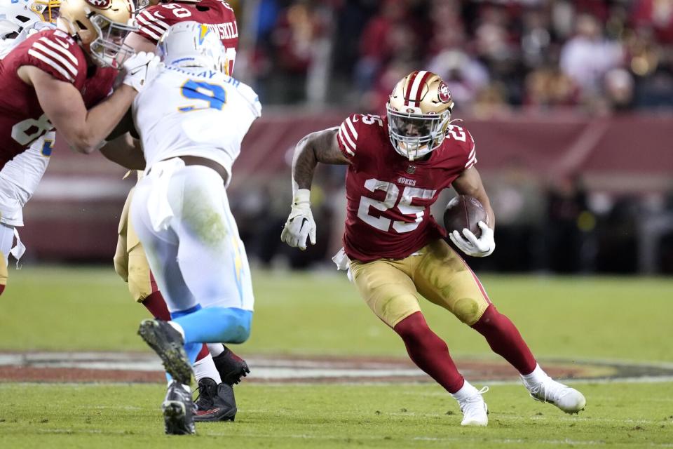 San Francisco 49ers running back Elijah Mitchell runs against Chargers linebacker Kenneth Murray Jr.