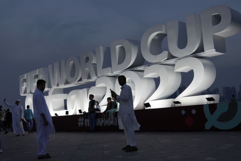 People pose for a photograph with a sign reading in English&quot; Fifa World Cup, Qatar 2022.