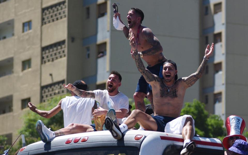 Argentina's Lionel Messi, Rodrigo De Paul, Leandro Paredes and teammates celebrate on the bus with the World Cup trophy during the victory parade - Reuters