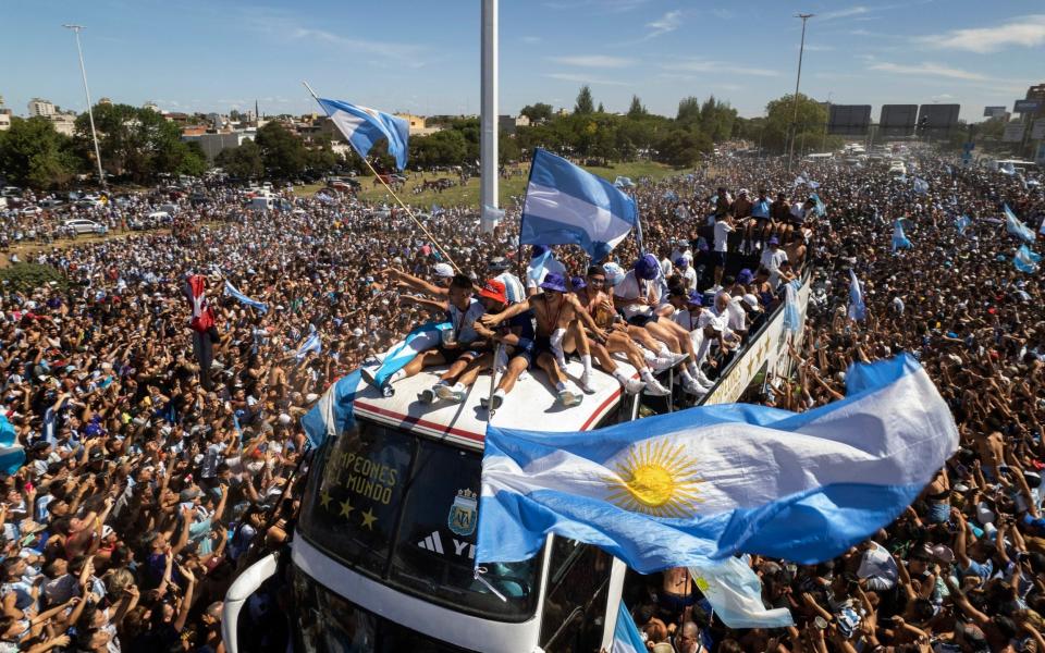 The Argentine soccer team that won the World Cup title ride on top of an open bus during their homecoming parade in Buenos Aires - AP