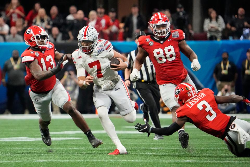 Dec 31, 2022; Atlanta, Georgia, USA; Ohio State Buckeyes quarterback C.J. Stroud (7) runs for a first down past Georgia Bulldogs defensive lineman Mykel Williams (13) and defensive back Kamari Lassiter (3) during the second half of the Peach Bowl in the College Football Playoff semifinal at Mercedes-Benz Stadium. Ohio State lost 42-41. Mandatory Credit: Adam Cairns-The Columbus Dispatch