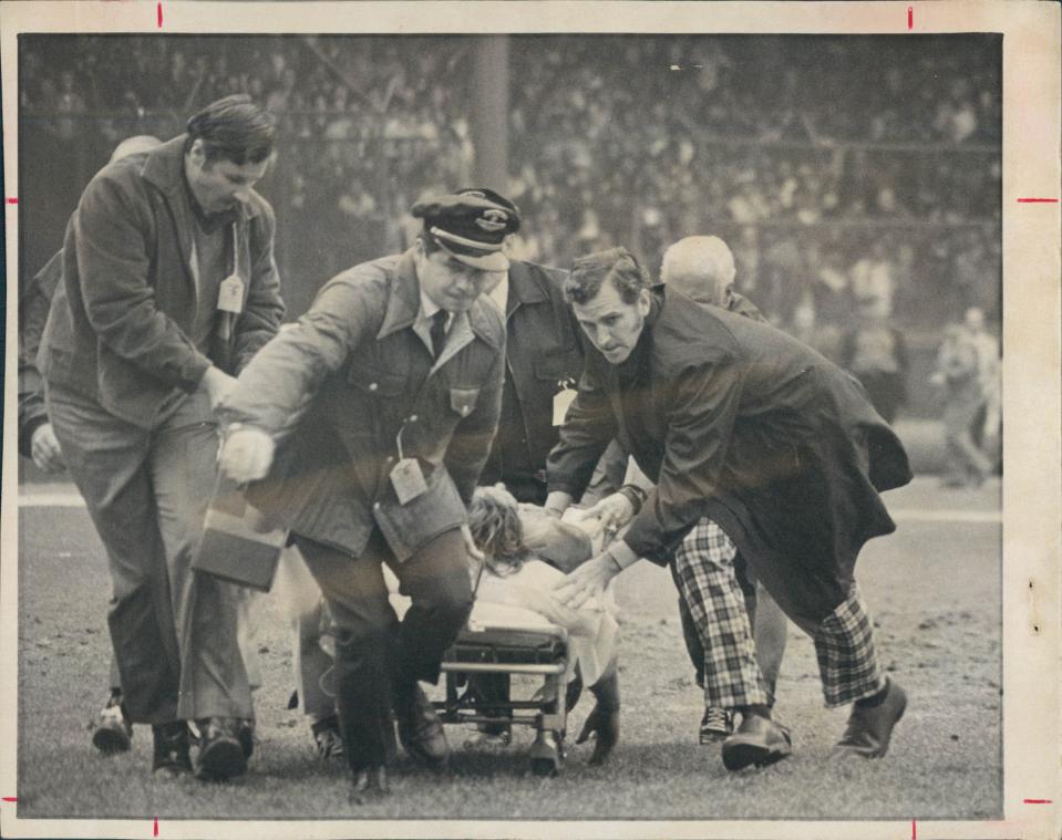 Lions receiver Chuck Hughes is rushed off the field on a gurney Oct. 24, 1971 at Tiger Stadium during a game vs. the Bears. In the plaid trousers is Dr. Eugene Boyle, an anesthesiologist from Grosse Pointe.