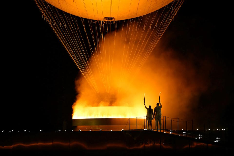 TOPSHOT - The torchbearers French former sprinter Marie-Jose Perec and French judoka Teddy Riner arrive to light the Olympic cauldron during the opening ceremony of the Paris 2024 Olympic Games in Paris on July 26, 2024. (Photo by MOHD RASFAN / AFP) (Photo by MOHD RASFAN/AFP via Getty Images)