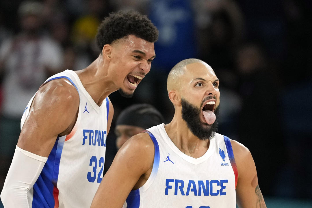 France's Evan Fournier, center, celebrates with France's Victor Wembanyama, right, after scoring during a men's basketball game against Canada at the 2024 Summer Olympics, Tuesday, Aug. 6, 2024, in Paris, France. (AP Photo/Michael Conroy)