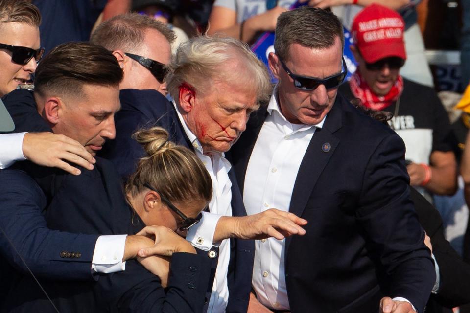 Donald Trump is seen with blood on his face surrounded by secret service agents as he is taken off the stage at a campaign event at Butler Farm Show Inc. in Butler, Pennsylvania, on July 13, 2024 (AFP via Getty Images)