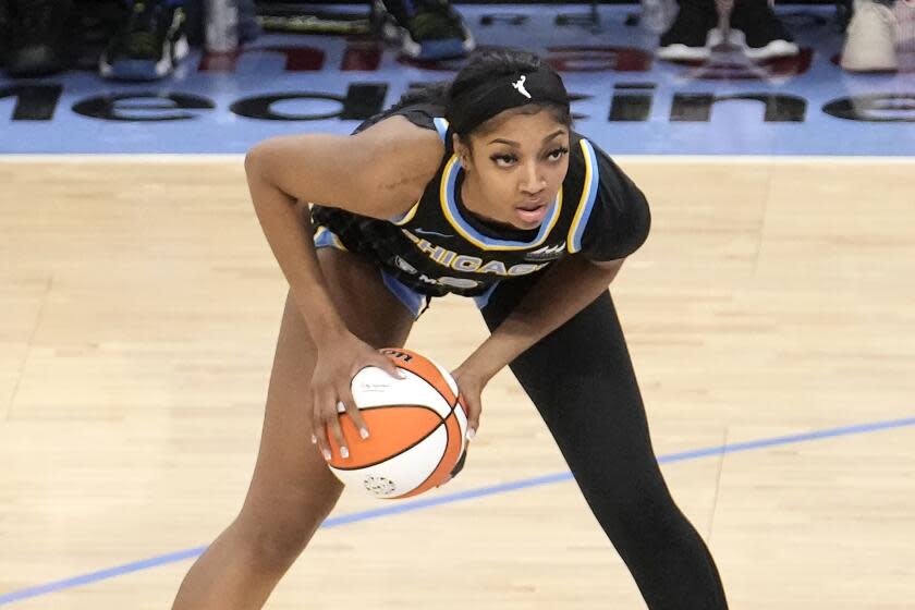 Chicago Sky's Angel Reese bends forward while looking to pass the ball. She's wearing a black sleeve on her left leg.