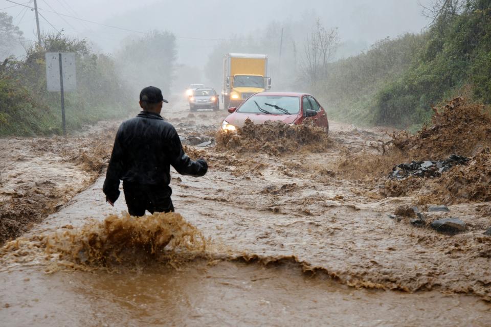 A local resident walks out into fast-flowing waters to assist a stranded driver on Friday in Boone, North Carolina (REUTERS/Jonathan Drake)