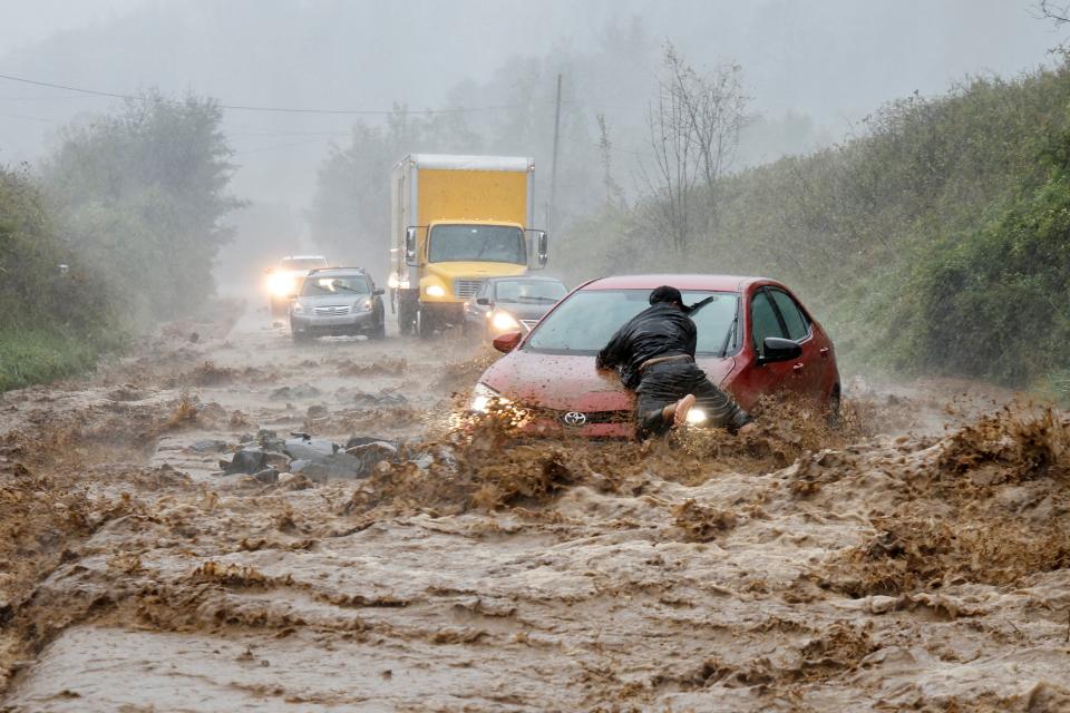 A local resident helps free a car that became stranded in a stretch of flooding road on Friday in Boone, North Carolina (REUTERS/Jonathan Drake)