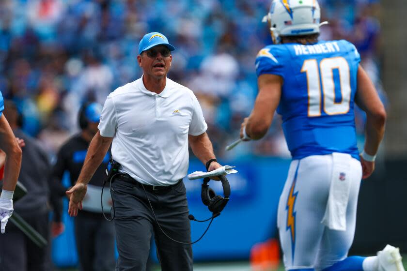 Chargers coach Jim Harbaugh meets Justin Herbert as he runs off the field against the Carolina Panthers.