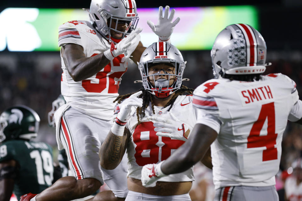 Ohio State tight end Gee Scott Jr., center, Ohio State running back TreVeyon Henderson, left, and Ohio State wide receiver Jeremiah Smith (4) celebrate Scott's touchdown during the first half of an NCAA college football game, Saturday, Sept. 28, 2024, in East Lansing, Mich. (AP Photo/Al Goldis)